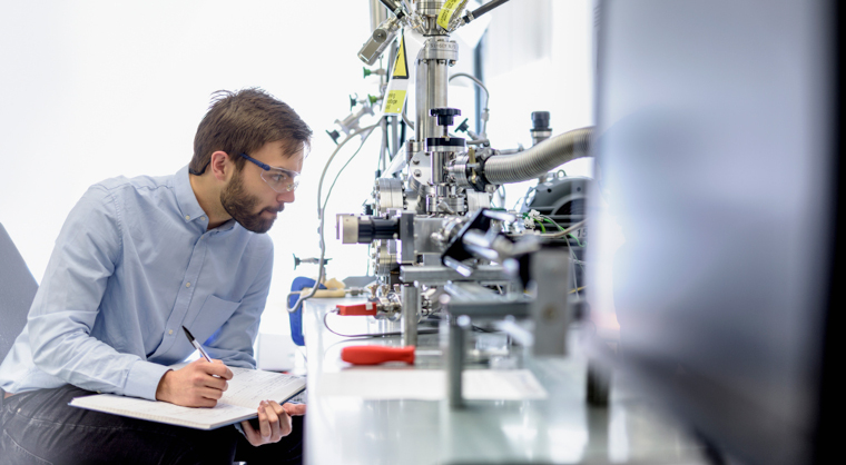 A scientist observes an experiment and makes notes.