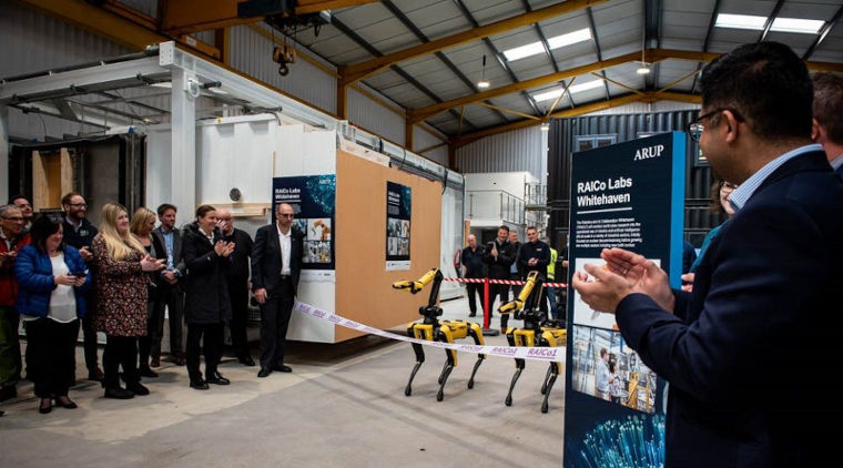 2 robotic dogs line up for the opening of RAICo1 facility in Whitehaven while people applaud.