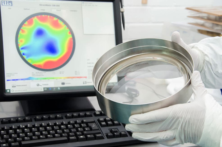 A scientist holding a viewport with the experiment graphic on a screen.