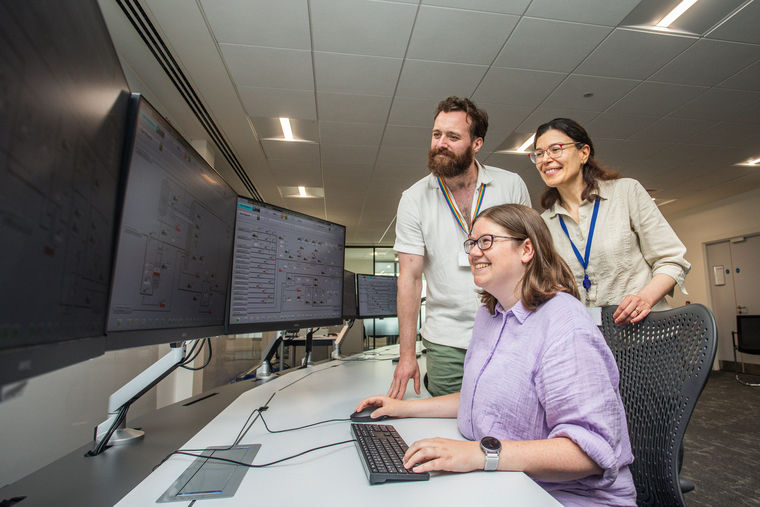 People gathered around a computer screen in a control room