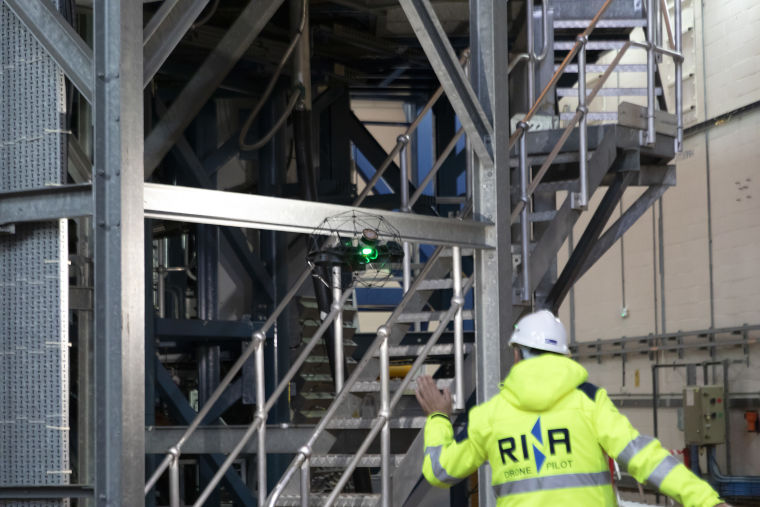 A drone pilot operates a drone in a fusion energy research facility.