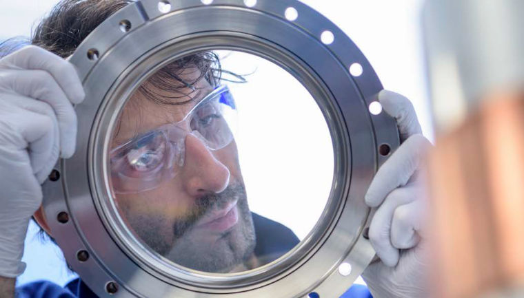 An expert at working in a laboratory inspects a specialist viewport.