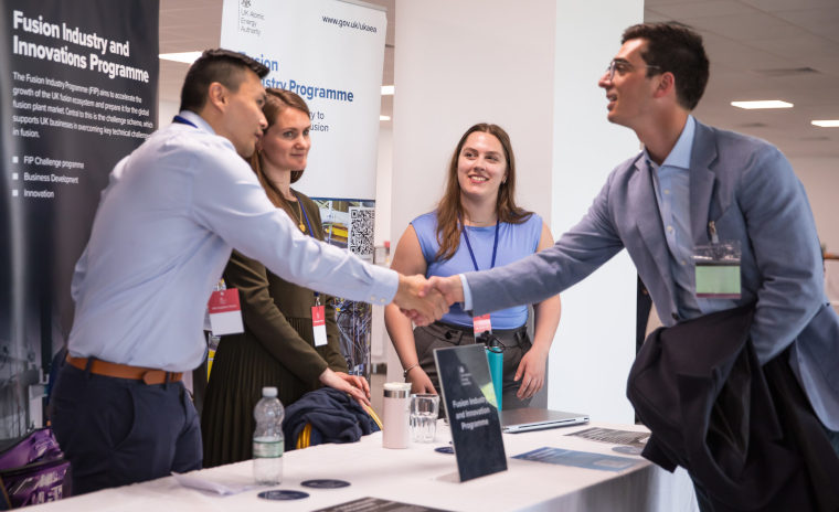Smartly-dressed people shake hands happily while meeting at an event.