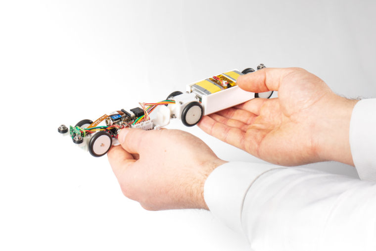 A robotics engineer holding a small long robot called a pipeineer designed to travel through a pipe.