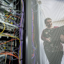 A computer expert working on a laptop next to some advanced computing equipment at the UK Atomic Energy Authority.