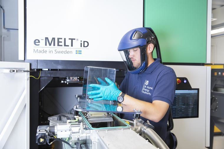 A specialist wearing a UK Atomic Energy Authority polo shirt working on an additive manufacturing project.