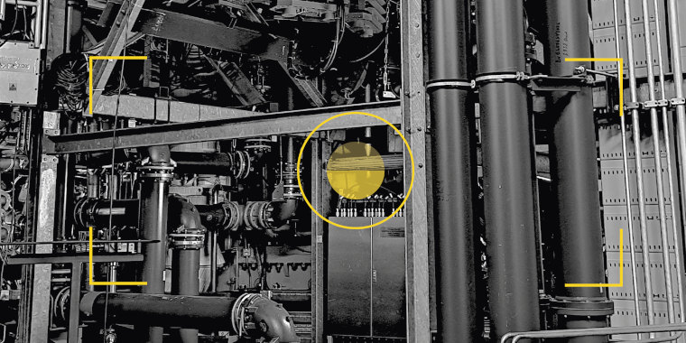 A complex fusion machine in black and white through the viewing lens of a camera. The centre point and framing marks are in yellow.