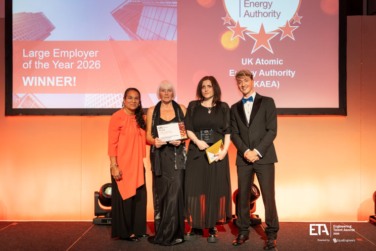 UKAEA employees collecting an award on stage in front of a screen which has Large Employer of the Year 2026 Winner!