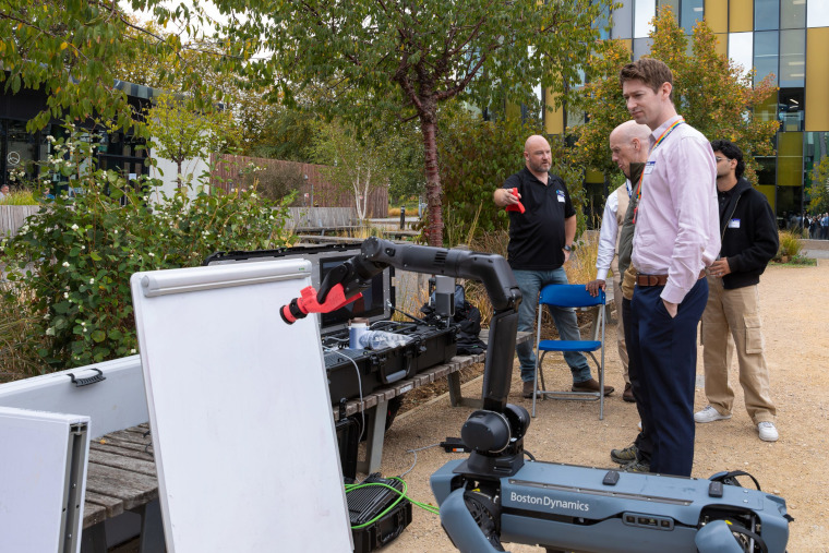 A group of experts watch a robot in action.